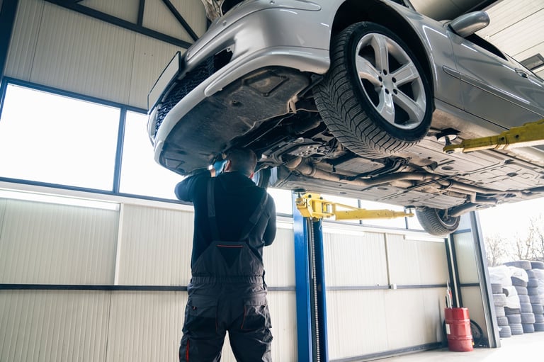 Mechanic checking car suspension on column lift